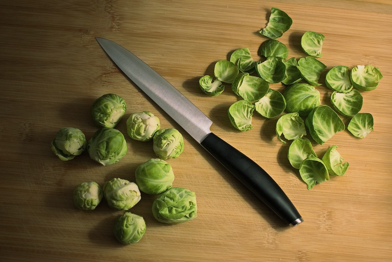 Brussels sprouts on butcher block counter chopped next to knife