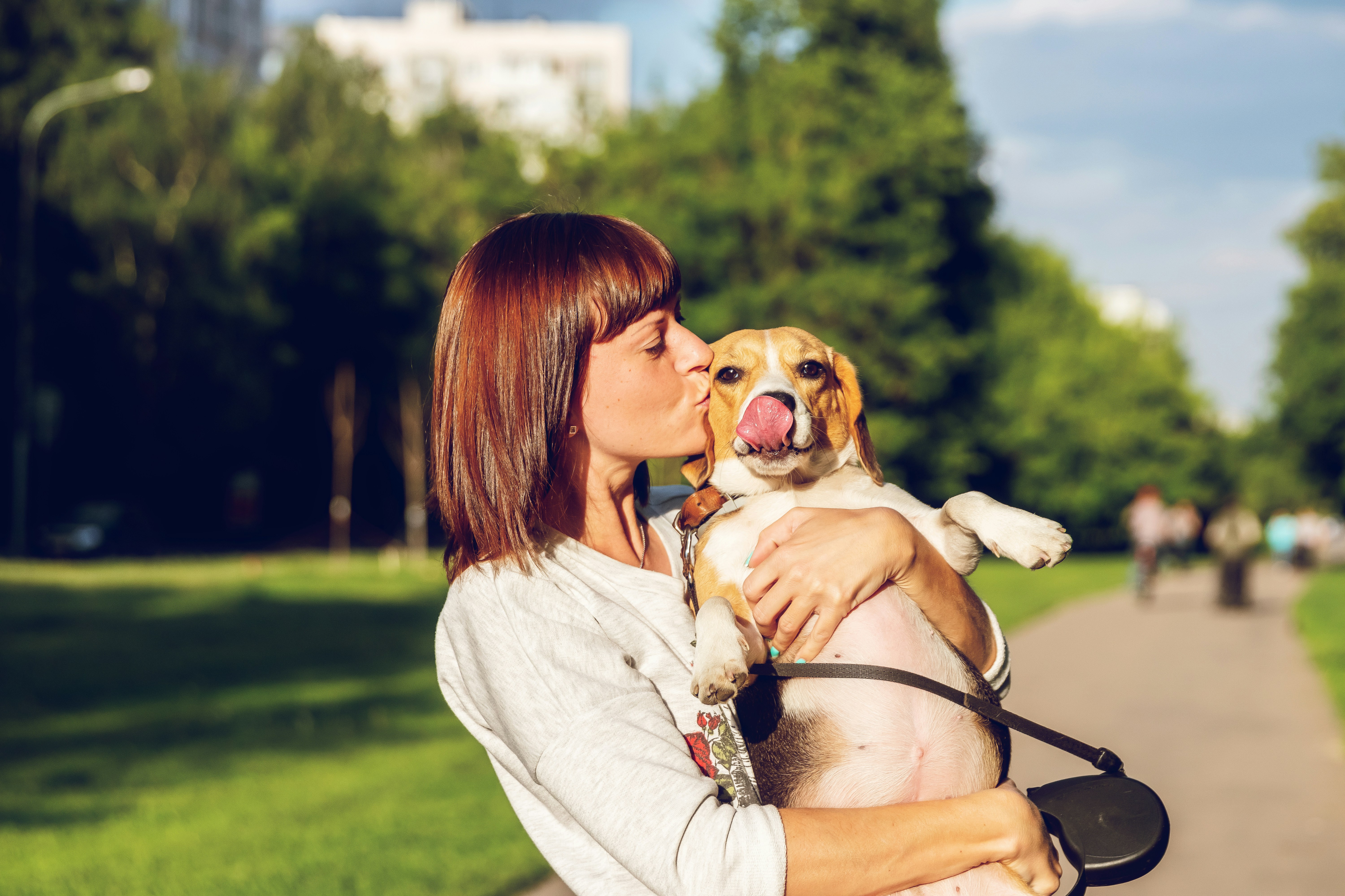 Woman outside holding a beagle and kissing their face.